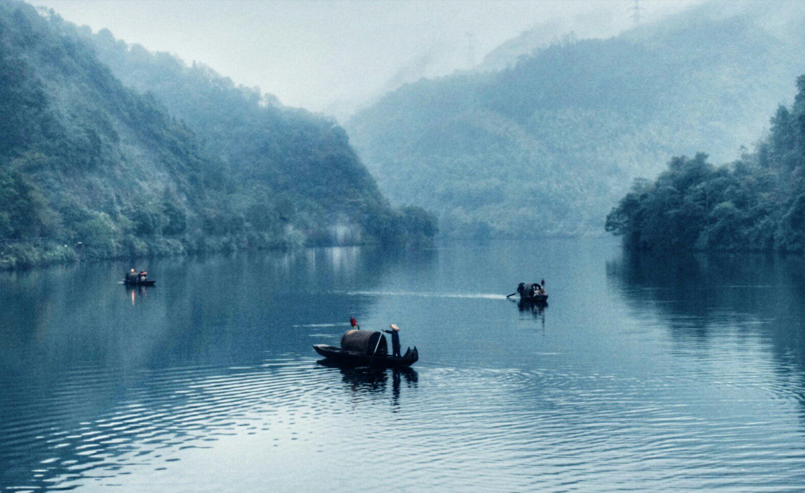Misty morning on the Xiaodongjiang section of Dongjiang Lake, Hunan, with small fishing boats drifting through river fog — Photo: 伊口 / CC BY 2.5 via Wikimedia Commons