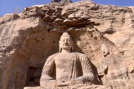The seated open-air Buddha of Cave 20 carved into the sandstone cliff at Yungang Grottoes, Datong