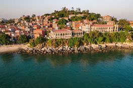 Aerial view of Gulangyu island in Xiamen: red-tiled rooftops and colonial villas on a wooded hill above a turquoise bay