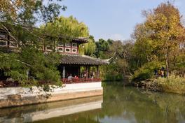 Waterside hall of the Humble Administrator's Garden in Suzhou with still water reflecting trees in autumn — Photo: King of Hearts / CC BY-SA 4.0 via Wikimedia Commons